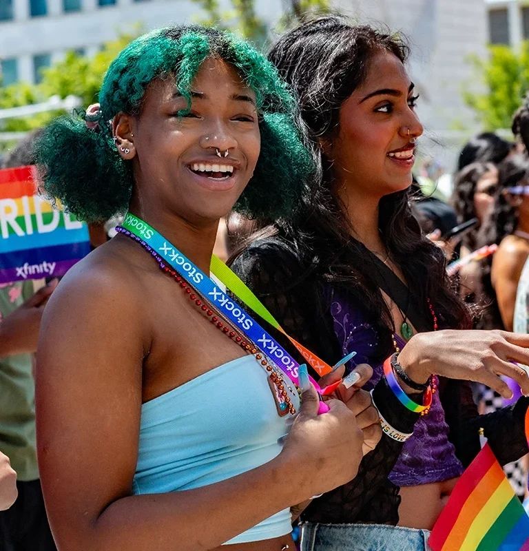 Smiling attendees with rainbow accessories at Motor City Pride