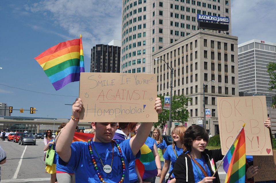 Marchers with signs and a rainbow flag at Motor City Pride 2012