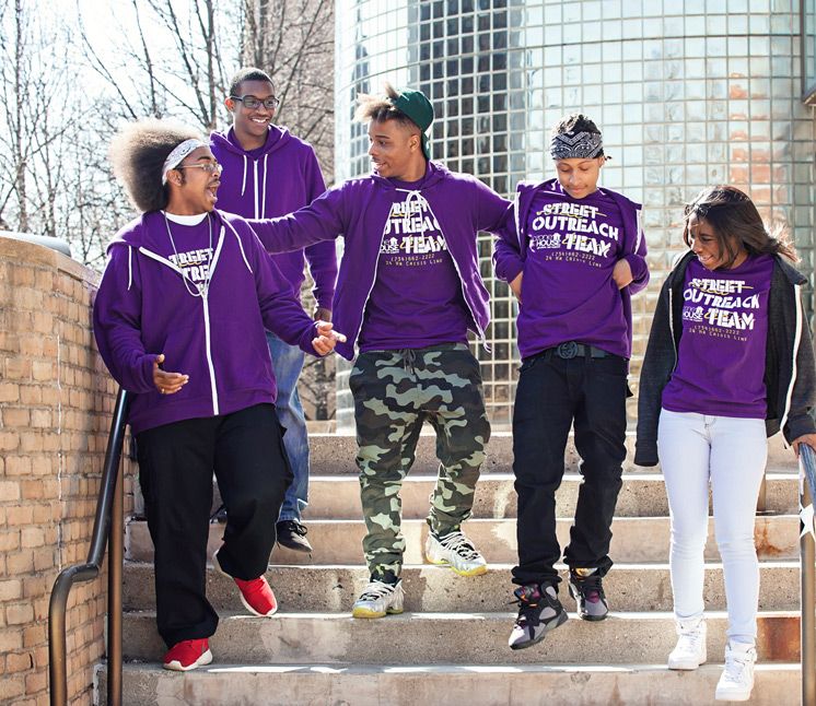 Young people in purple Street Outreach Team hoodies on outdoor steps