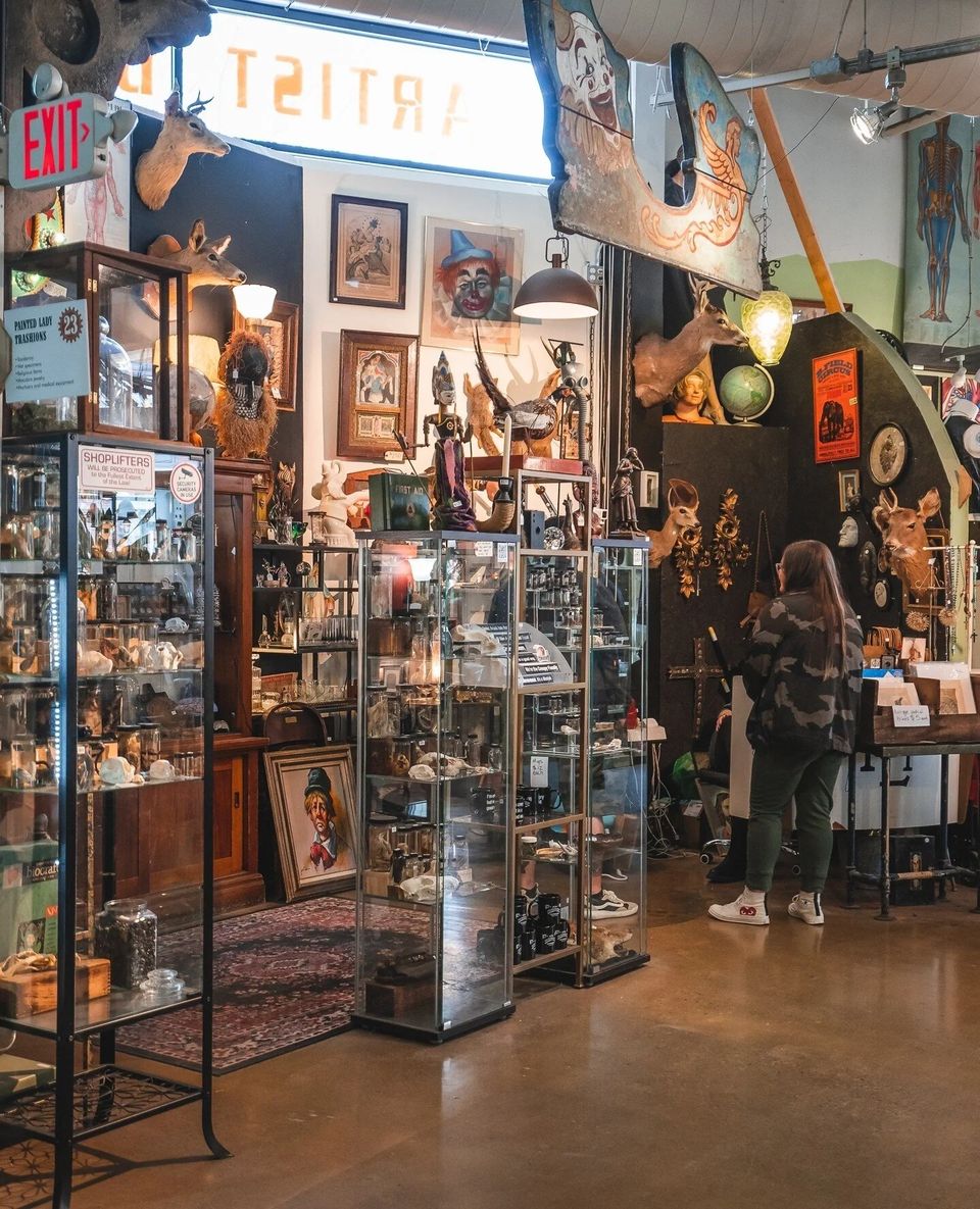 Vendor booth packed with vintage curios, paintings and glass display cases