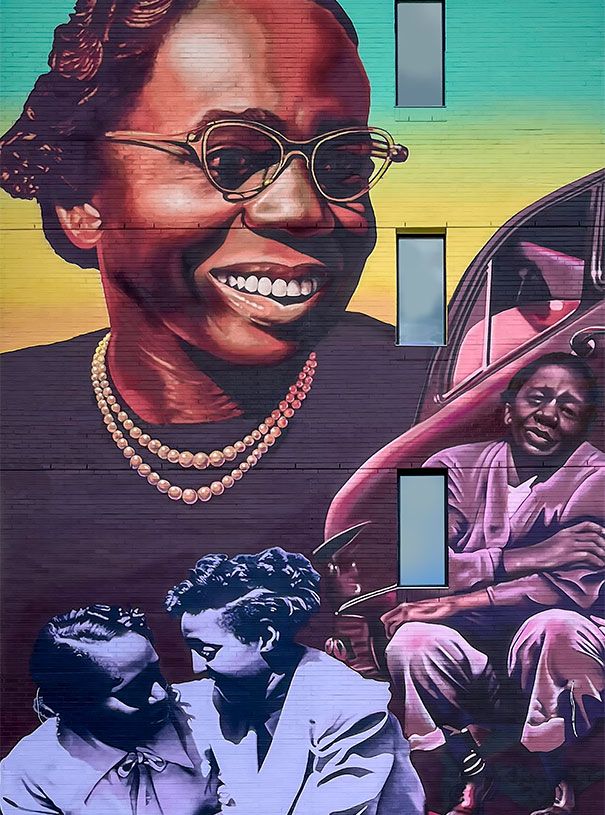 Colorful mural of a smiling woman in glasses and an embracing couple