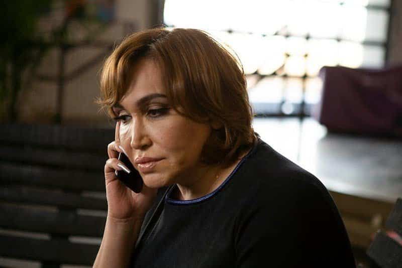 Woman with a serious expression talking on the phone indoors