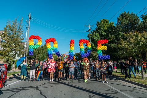 Pride march with rainbow PRIDE balloon letters on a sunny street
