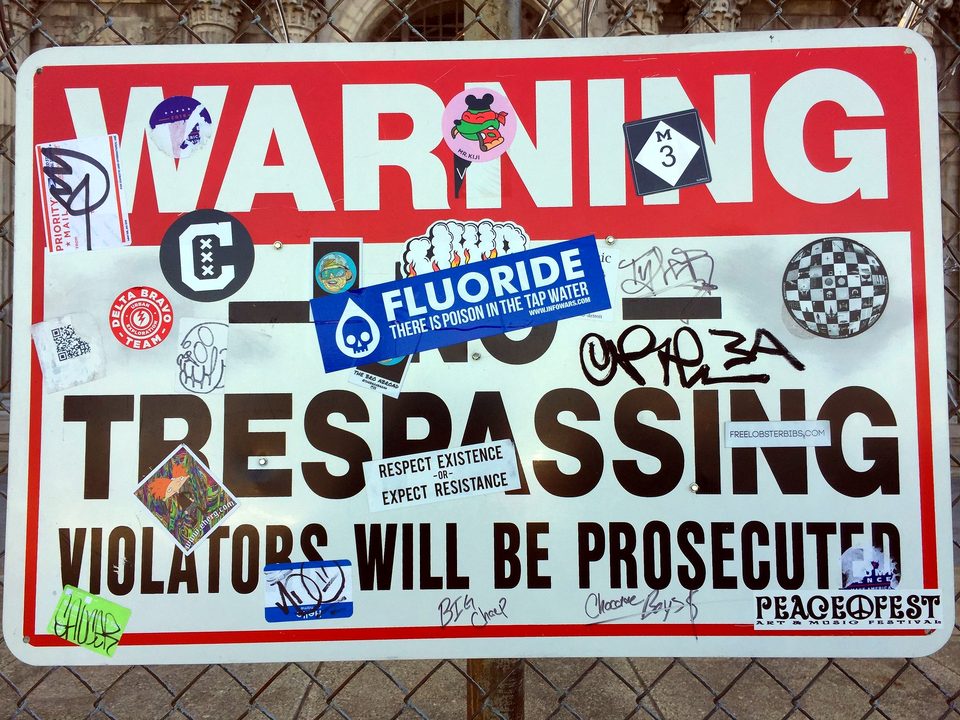 A sticker-covered No Trespassing sign on the fence, 2017