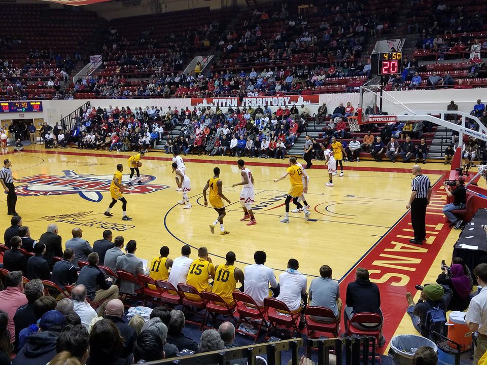 Basketball at Calihan Hall, Detroit Mercy and Oakland players on the floor, with the bench and fans alongside