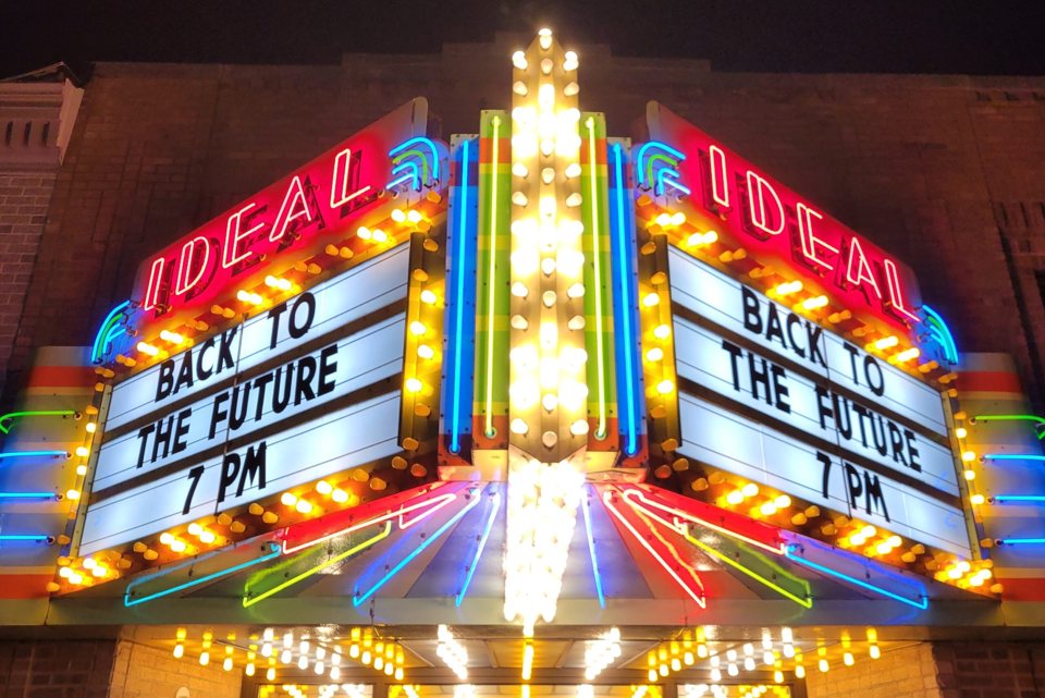 The Ideal's marquee blazing with colored neon and bulbs at night, its boards announcing Back to the Future at 7 PM