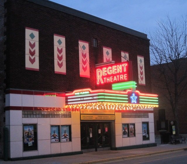 The Regent Theatre's brick facade at dusk, with its red neon sign and lit marquee