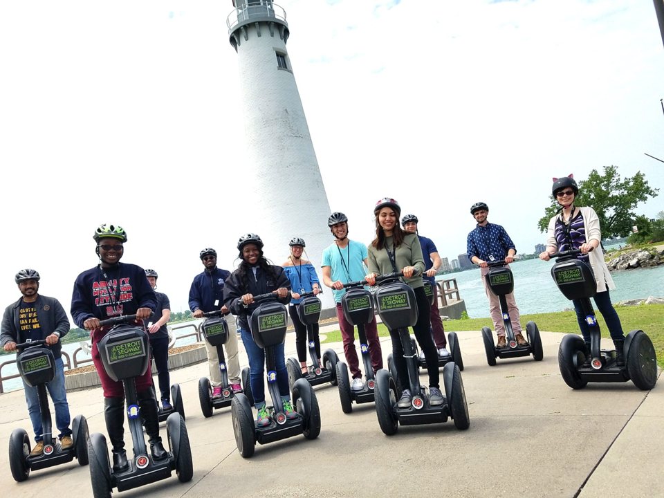 A large group on Segways poses in front of the lighthouse at Milliken State Park